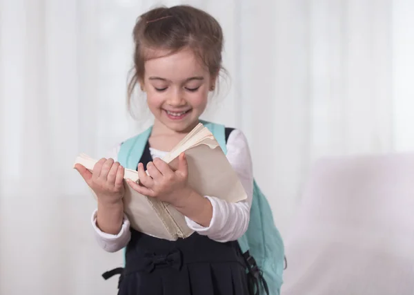 Girl-elementary school student with a backpack and a book — Stock Photo, Image