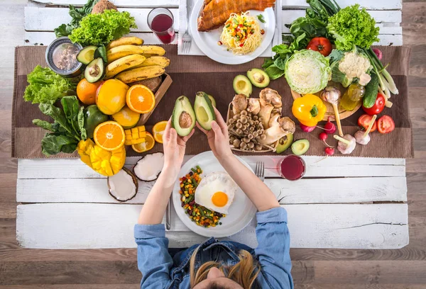 De vrouw aan de eettafel met biologisch eten, het uitzicht vanaf de top. — Stockfoto