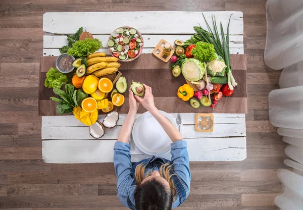 A mulher na mesa de jantar com comida orgânica, a vista do topo . — Fotografia de Stock