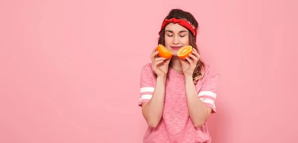 Портрет девушки с апельсинами в руке, на розовом фоне — стоковое фото