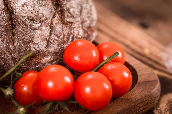 Fresh small organic tomatoes on a wooden plate close-up — Stock Photo, Image