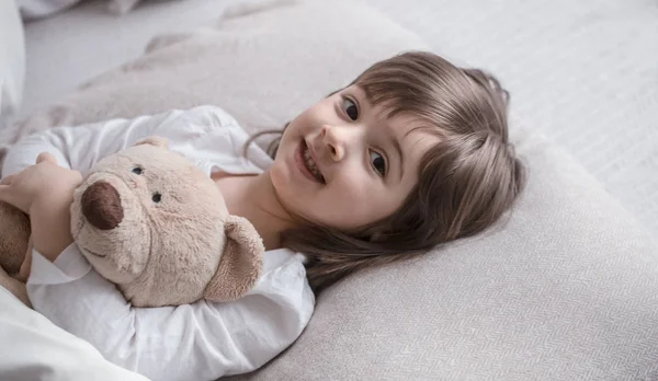 Oyuncak ile yatakta küçük sevimli kız