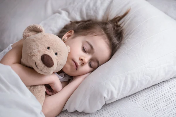 Kleines süßes Mädchen im Bett mit Spielzeug — Stockfoto