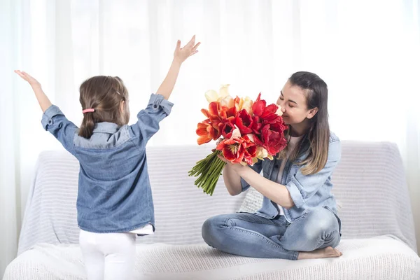 День Матери. Маленькая дочь с цветами поздравляет свою мать — стоковое фото