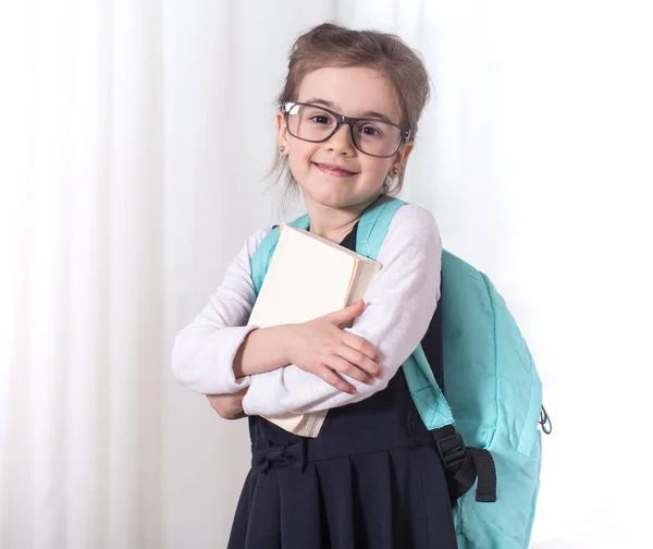 Girl-elementary school student with a backpack and a book — Stock Photo, Image