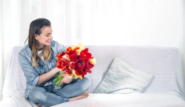 Young girl with a bouquet of tulips in the living room