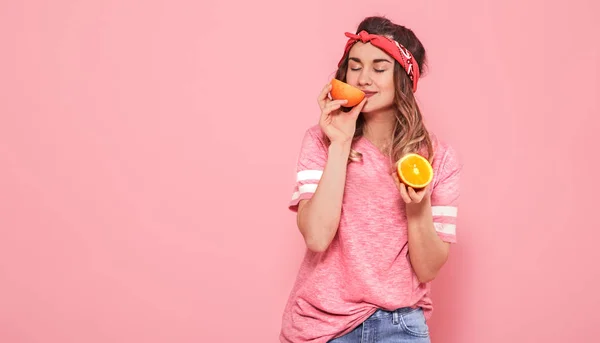Портрет девушки с апельсинами в руке, на розовом фоне — стоковое фото