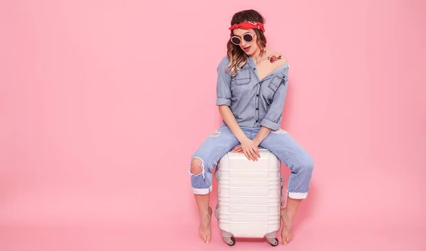 Портрет девушки с чемоданом на розовом фоне — стоковое фото