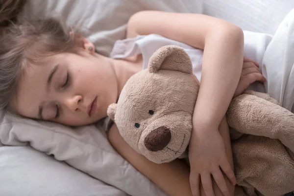 Kleines süßes Mädchen im Bett mit Spielzeug — Stockfoto