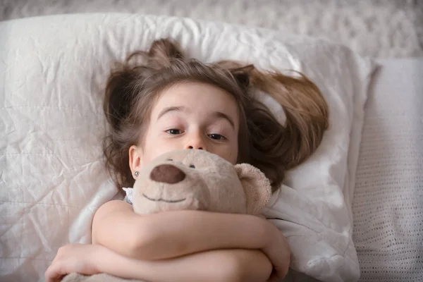 Kleines süßes Mädchen im Bett mit Spielzeug — Stockfoto