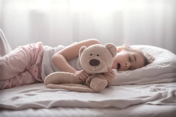 Kleines süßes Mädchen im Bett mit Spielzeug — Stockfoto