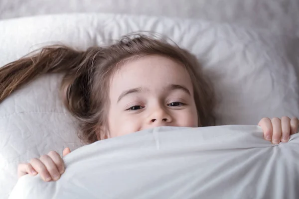 Μικρό χαριτωμένο κορίτσι χαμογελά στο κρεβάτι, αίσθηση του ύπνου — Φωτογραφία Αρχείου