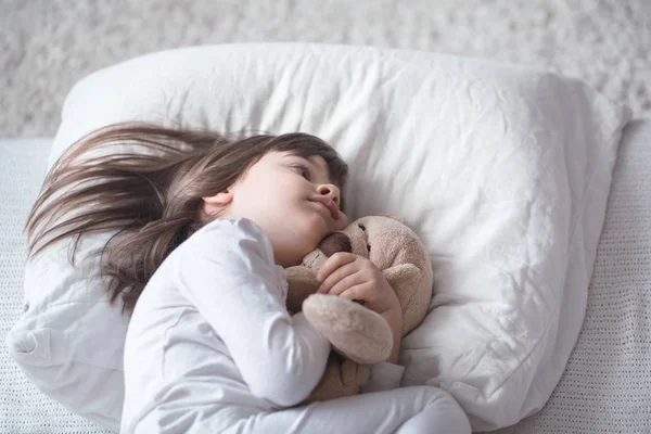 Маленька мила дівчинка в ліжку з іграшкою — стокове фото