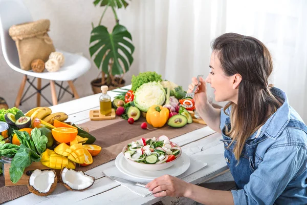 Junge und glückliche Frau isst Salat am Tisch — Stockfoto