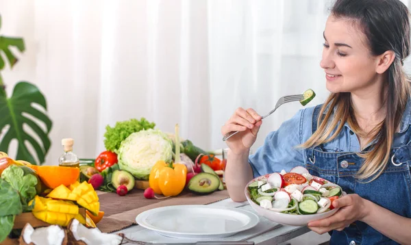 Mujer joven y feliz comiendo ensalada en la mesa — Foto de Stock