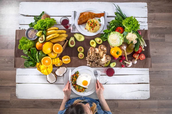 A mulher na mesa de jantar com comida orgânica, a vista de — Fotografia de Stock