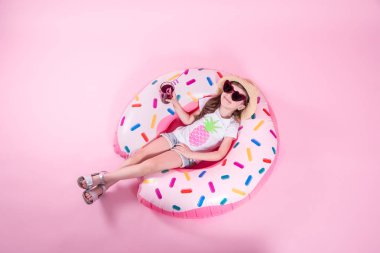 Küçük bir çocuk kız bir donut şişme daire üzerinde yatıyordu. Pembe bac