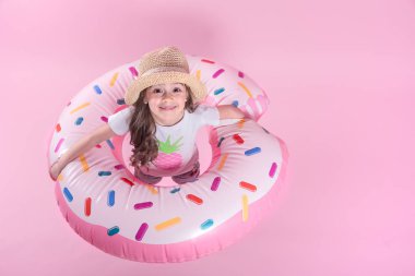 Küçük bir çocuk kız bir donut şişme daire üzerinde yatıyordu. Pembe bac