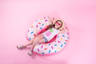 Küçük bir çocuk kız bir donut şişme daire üzerinde yatıyordu. Pembe bac