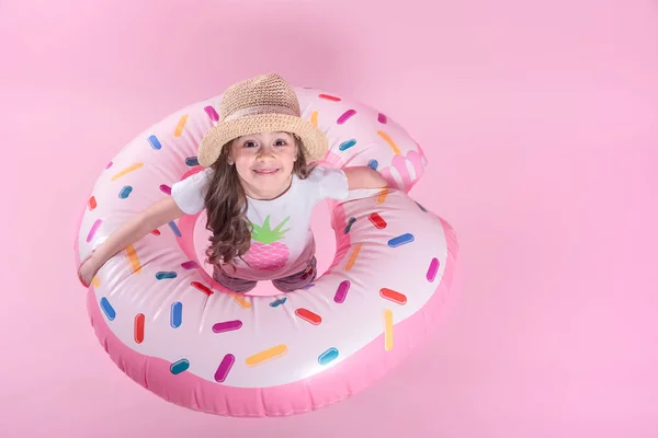 Una niña pequeña acostada en un círculo inflable de donas. Bacalao rosa —  Fotos de Stock