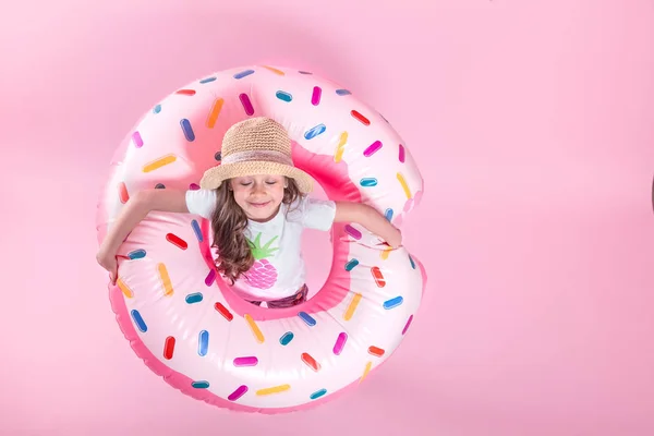 Küçük bir çocuk kız bir donut şişme daire üzerinde yatıyordu. Pembe bac — Stok fotoğraf