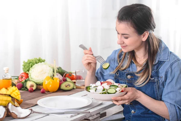 Mujer joven y feliz comiendo ensalada en la mesa —  Fotos de Stock