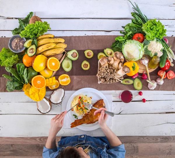 De vrouw aan de eettafel met biologisch eten, het uitzicht vanaf — Stockfoto