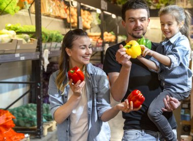 Mutlu aile sebze satın alır. Süpermarket veya Pazar sebze bölümünde üç seçimi domates neşeli aile.
