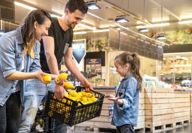 Süpermarkette limon ve meyve seçen aile