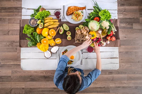 De vrouw aan de eettafel met biologisch eten, het uitzicht vanaf de top. — Stockfoto