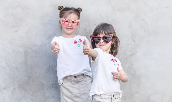 Cheerful little girls on gray textured background. Outdoor portrait little girl. Gray textured wall background. — Stock Photo, Image