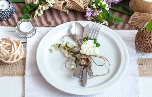 Splendidamente elegante tavolo decorato per le vacanze - matrimonio o San Valentino con posate moderne, arco, vetro, candela e regalo — Foto Stock