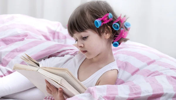 Linda niña sonriendo mientras está acostada en una acogedora cama blanca —  Fotos de Stock