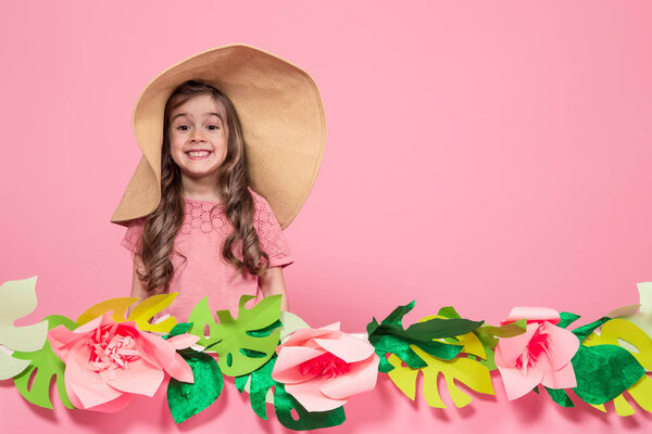 Portrait of a little girl in a summer hat on a pink background