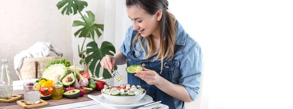 Young and happy woman eating salad at the table — Stock Photo, Image