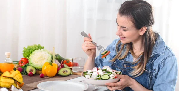 Mujer joven y feliz comiendo ensalada en la mesa — Foto de Stock