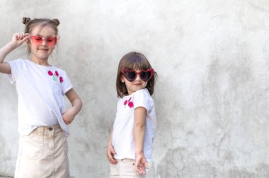 Gri dokulu arka planda neşeli küçük kızlar. Açık hava portresi küçük kız. Gri dokulu duvar arka planı.