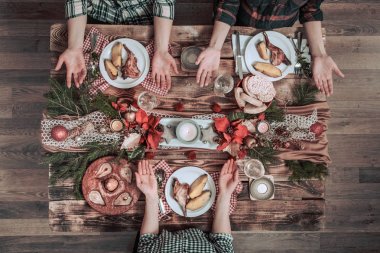 Arkadaşların elleri birlikte yiyip içiyor. Ahşap rustik masada birlikte parti yapan, toplayan, kutlayan insanların üst görünümü