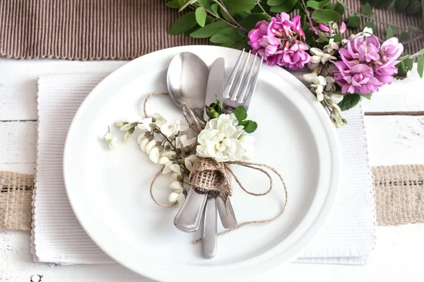 Splendidamente elegante tavolo decorato per le vacanze - matrimonio o San Valentino con posate moderne, arco, vetro, candela e regalo — Foto Stock
