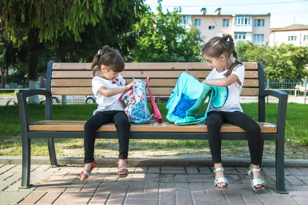 Okula dönüyoruz. Bankta oturan mutlu sevimli çalışkan çocuklar — Stok fotoğraf