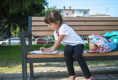 Sırt çantası olan bir ilkokul öğrencisi ben oturuyor