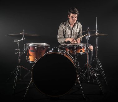 Profesyonel davulcu siyah arka plan üzerinde sahnede davul seti oynuyor