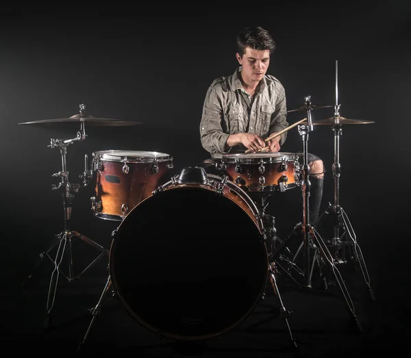 Професійний барабанщик, який грає на барабані на сцені на чорному тлі — стокове фото