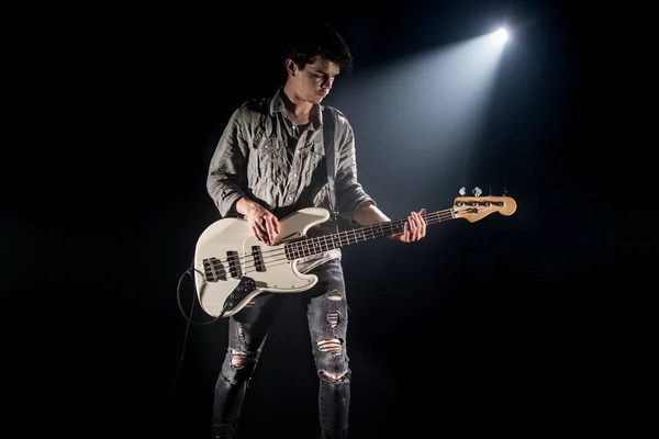 the musician plays bass guitar, on a black background with a bea