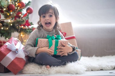 Güzel küçük kız bir hediye kutusu tutuyor ve zaman Sitti gülümseyen