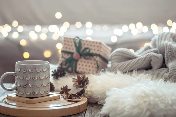 Coffee cup over Christmas lights bokeh in home on wooden table w — Stock Photo, Image