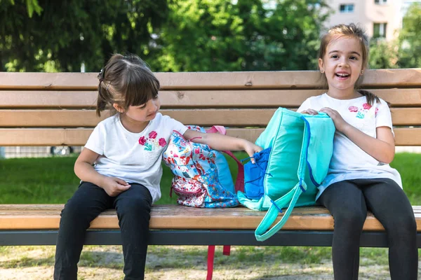Torniamo a scuola. Felice carino bambini laboriosi seduti sulla panchina e parlare. Concetto di istruzione di successo . — Foto Stock