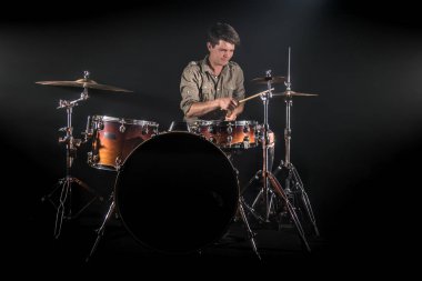 Profesyonel davulcu siyah arka plan üzerinde sahnede davul seti oynuyor