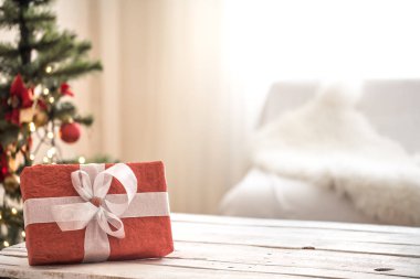 Pencerenin yakınındaki ahşap masaüzerinde Açık arka plan üzerinde Kırmızı Noel hediyesi. Noel süsleri
