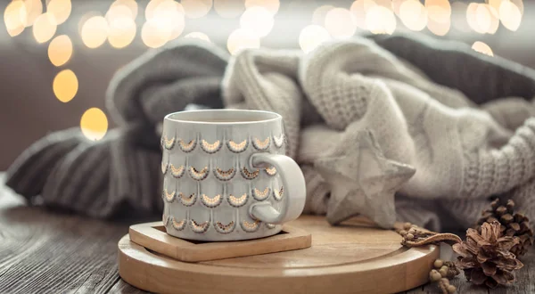 Kaffeetasse über Weihnachtsbeleuchtung bokeh in Hause auf Holztisch mit Pullover auf einem Hintergrund und Dekorationen. Weihnachtsdekoration, magische Weihnachten — Stockfoto